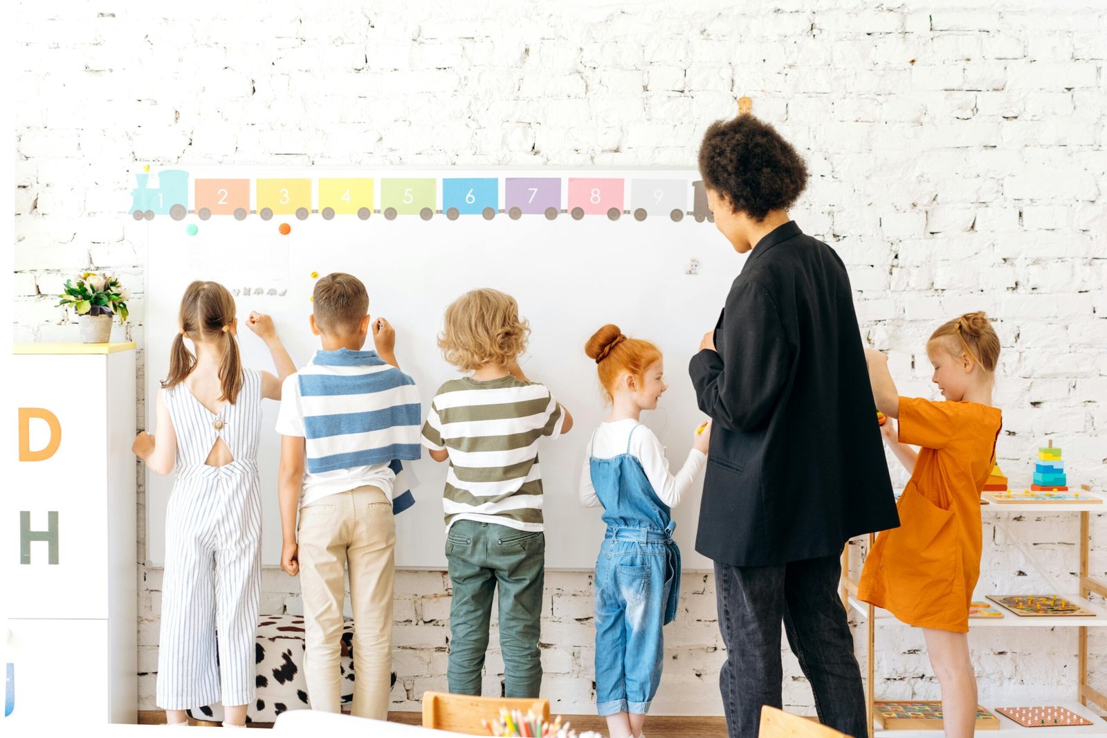 pexels-photo-8923027-8923027 Group of children and teacher interacting with a whiteboard in a bright, indoor classroom setting.